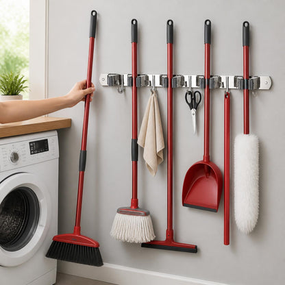 Broom holder on a laundry room wall holding brooms, mop and dustpan